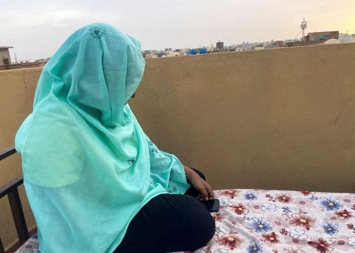 Heba checks her phone for news of her relatives as she sits on the rooftop of her house during the conflict in Khartoum, Sudan, April 30, 2023. REUTERS/El Tayeb Siddig