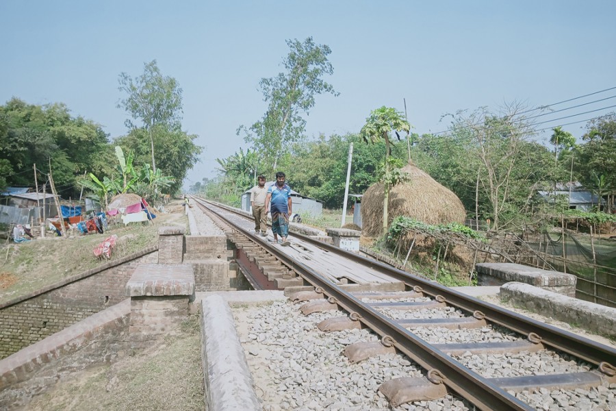 The photo shows people walking along a railway track in Badiyakhali area under Sadar upazila of Gaibandha district — FE Photo