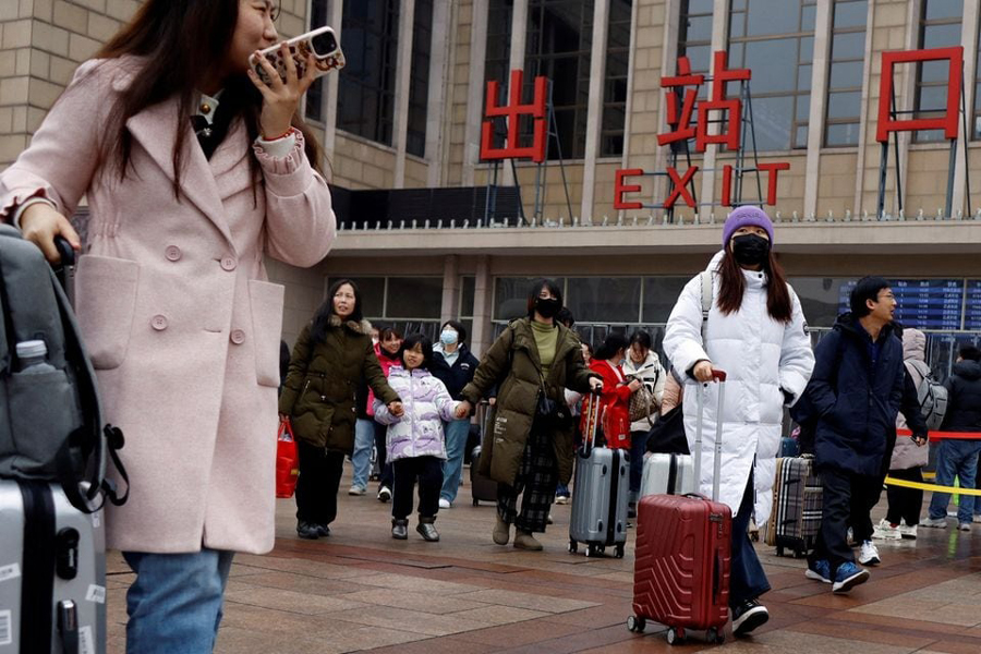 Travellers walk with their luggage outside the Beijing railway station during the Spring Festival travel rush following the eight-day Lunar New Year holiday, in Beijing, China February 18, 2024.