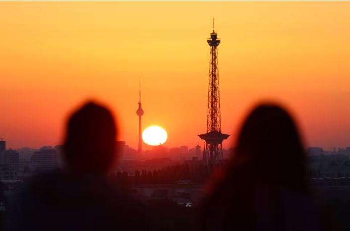 People watch the rising sun which illuminates Berlin's skyline, framing the Fernsehturm (Television Tower) and the Berliner Funkturm (Berlin Radio Tower), Germany, September 7, 2023. REUTERS/Fabrizio Bensch/File Photo