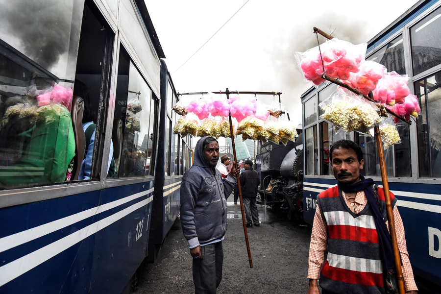 Vendors sell candy floss to passengers as Darjeeling Himalayan Railway trains, which runs on a two foot gauge railway and is a UNESCO World Heritage Site, arrive at a station in Ghum, June 25, 2019.