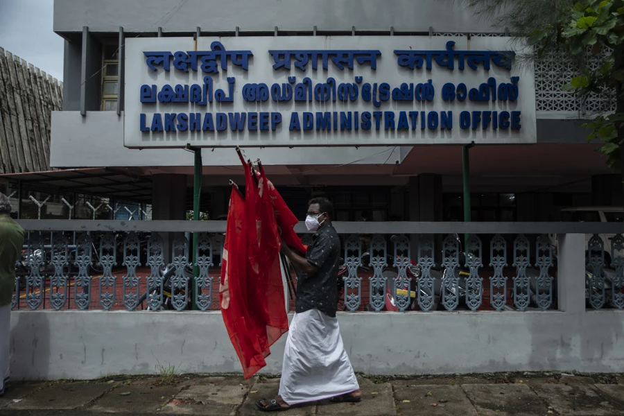 An activist of Centre of Indian Trade Unions (CITU) walks with flags after a protest outside the Lakshadweep administration office in Kochi, Kerala state, India, June 15, 2021. India announced plans for a new naval base off the country’s south-west coast and close to Maldives, as tensions are running high between Delhi and the island nation. The Indian Navy said Saturday it plans to build a base called INS Jatayu on Minicoy, the southernmost island in the Lakshadweep archipelago