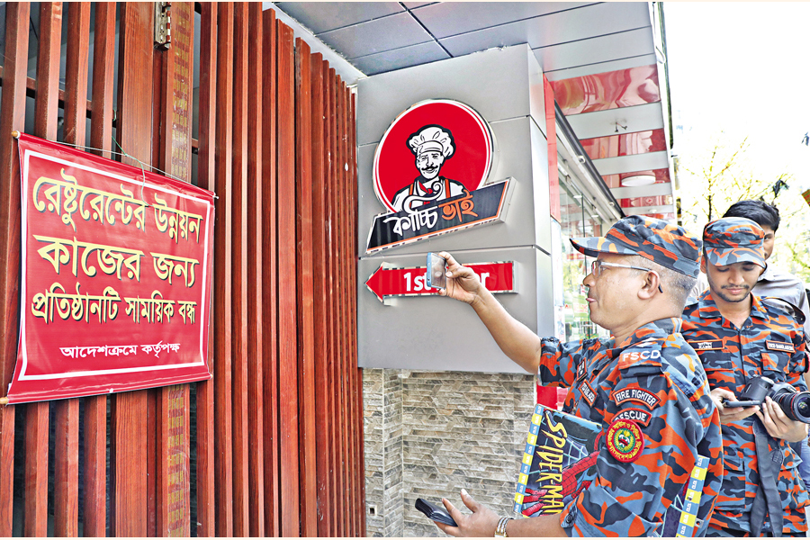 Fire service and Dhaka South City Corporation officials photograph the shuttered 'Kacchi Bhai' biriyani restaurant in Khilgaon area of Dhaka, following the Bailey Road fire. Banners on several closed restaurants claim "out of service due to temporary development works". — FE Photo