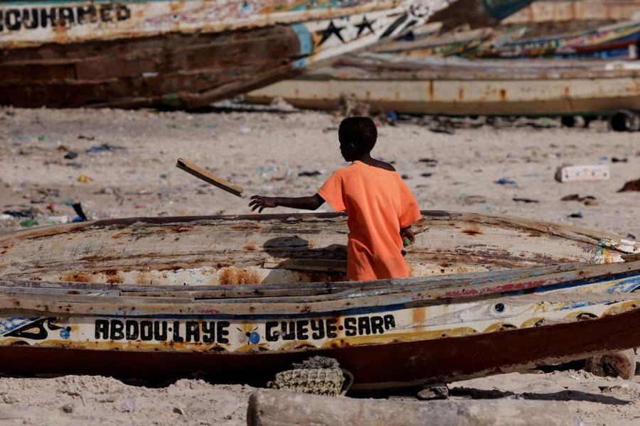A boy cleans a Senegalese fishing pirogue on the beach in Bargny on the outskirts of Dakar, Senegal March 7, 2024.
