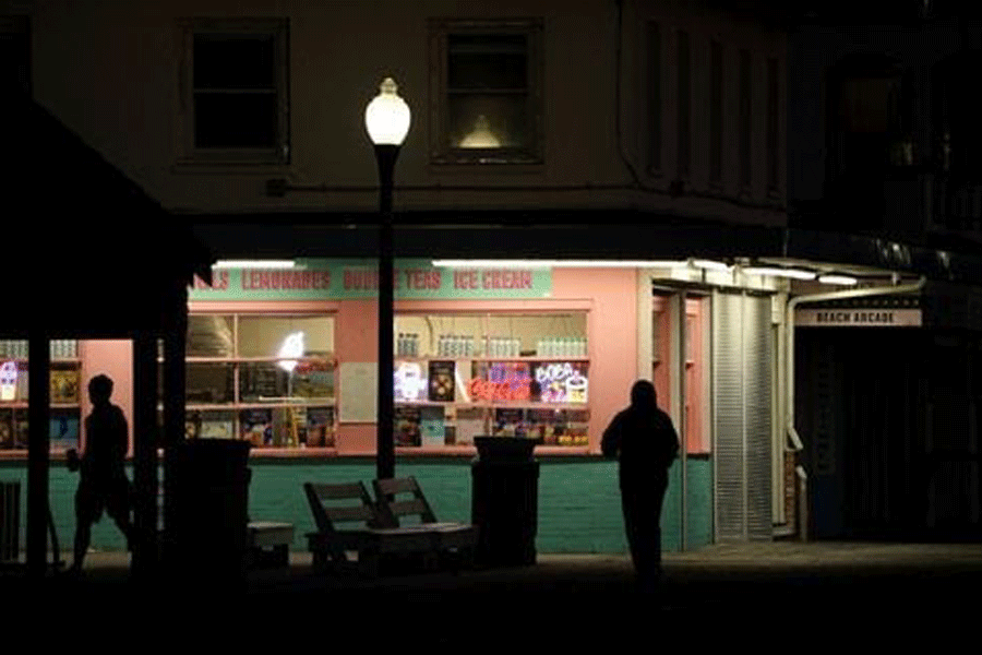 People walk past an ice cream shop at dawn along the boardwalk at Rehoboth Beach, Delaware, US, October 18, 2023.