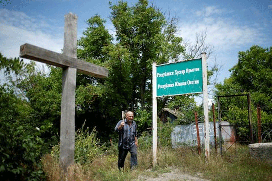 A local resident Marab Mekarishvili, 57, walks past a banner “Republic Of South Ossetia” at the borderline on the de facto border of Georgia’s breakaway region of South Ossetia in Dvani, Georgia, June 4, 2018.