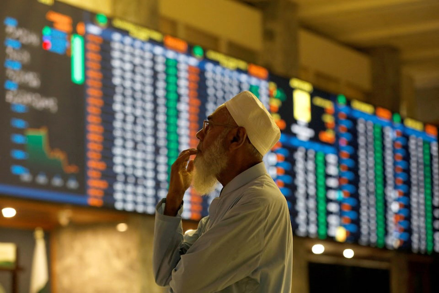 A stock broker reacts while monitoring the market on the electronic board displaying share prices during trading session at the Pakistan Stock Exchange, in Karachi, Pakistan July 3, 2023.