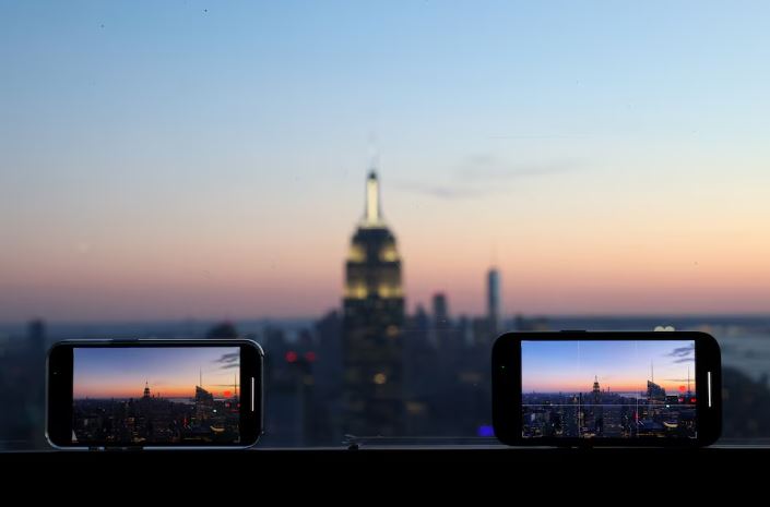 Smartphones are used to record the skyline at sunset in Manhattan, in New York City, New York U.S., February 11, 2022. REUTERS/Andrew Kelly/File Photo
