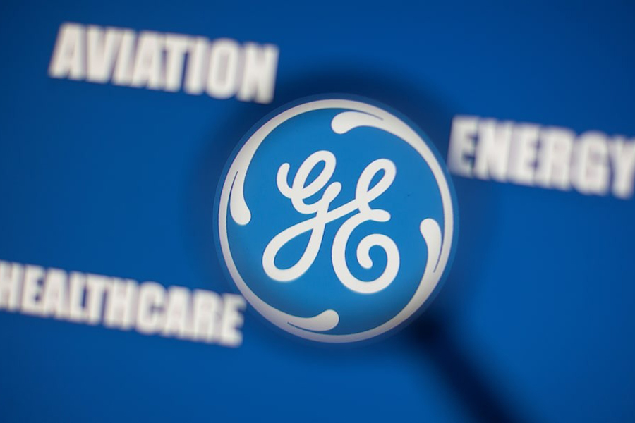 General Electric logo is seen through magnifier in front of displayed Aviation, Energy, Healthcare words in this illustration taken, November 9, 2021.