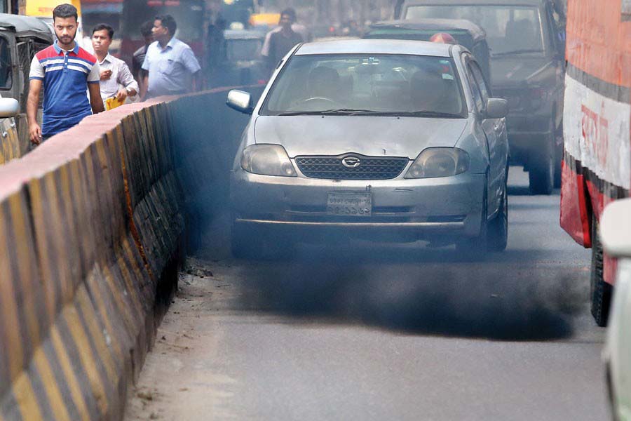 A bus spewing a cloud of black smoke while plying a city street.