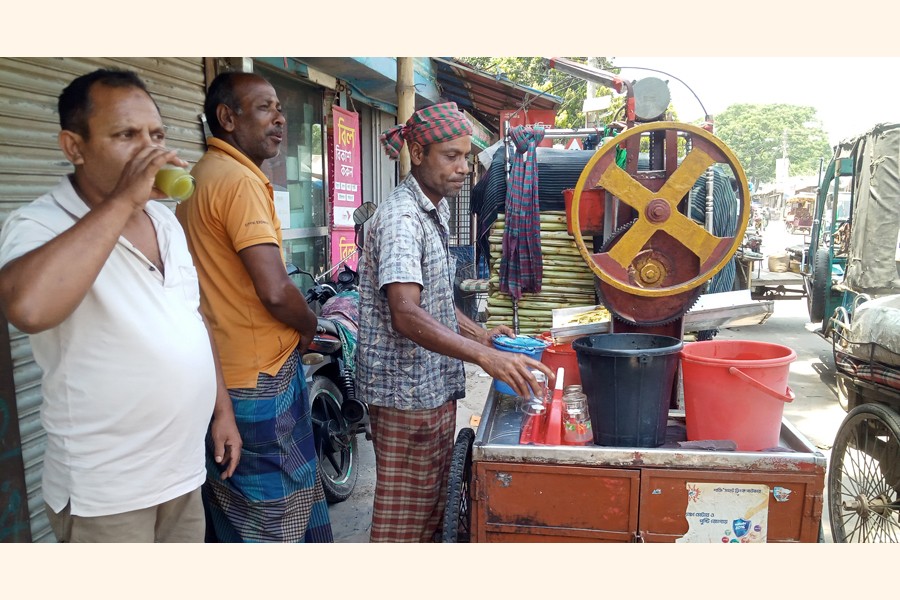 Amid the sweltering heat, people trying to quench their thirst by drinking sugarcane juice at a roadside shop in Gaibandha town — FE Photo