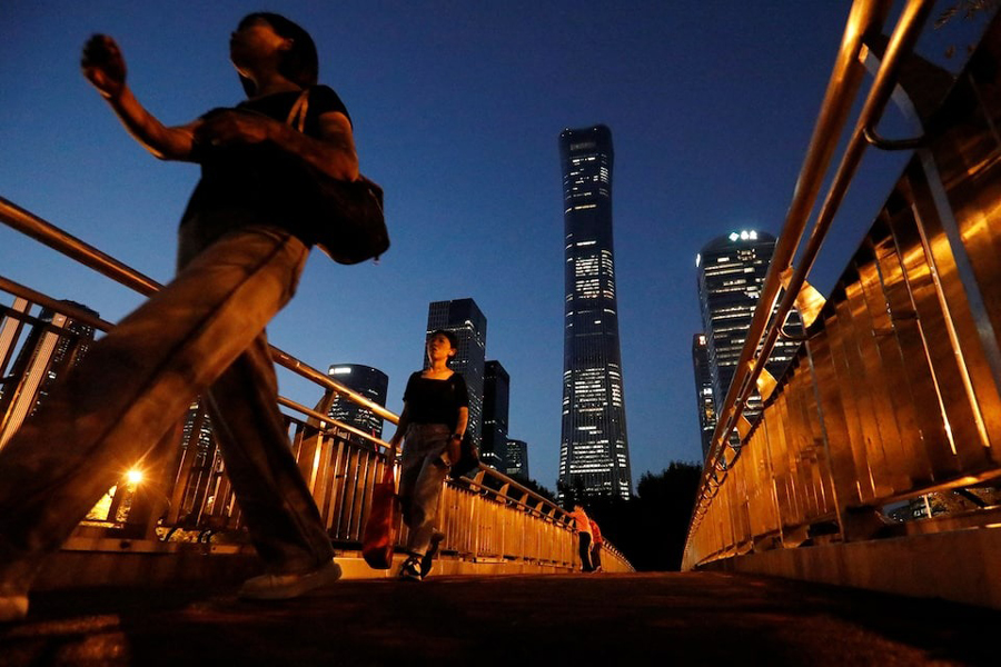 Pedestrians walk on an overpass near skyscrapers at the Central Business District in Beijing, August 21, 2023.