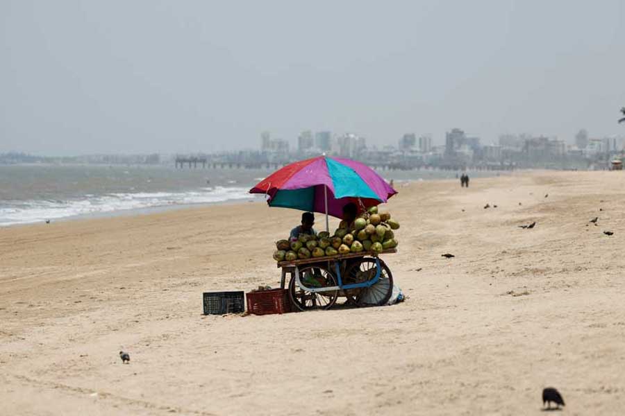 A vendor selling coconut water waits for customers at a beach on a hot day in Mumbai, India, April 29, 2024.