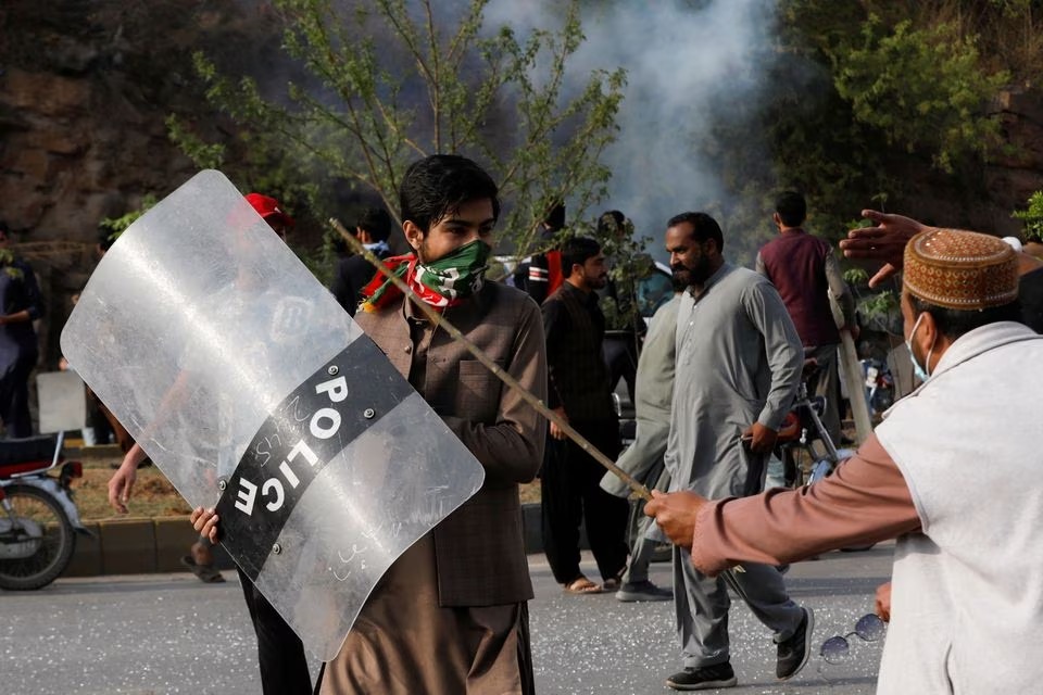 A supporter of former Pakistani Prime Minister Imran Khan, walks with a riot shield used by the police, during a clash outside the federal judicial complex in Islamabad, Pakistan on March 18, 2023 — Reuters photo