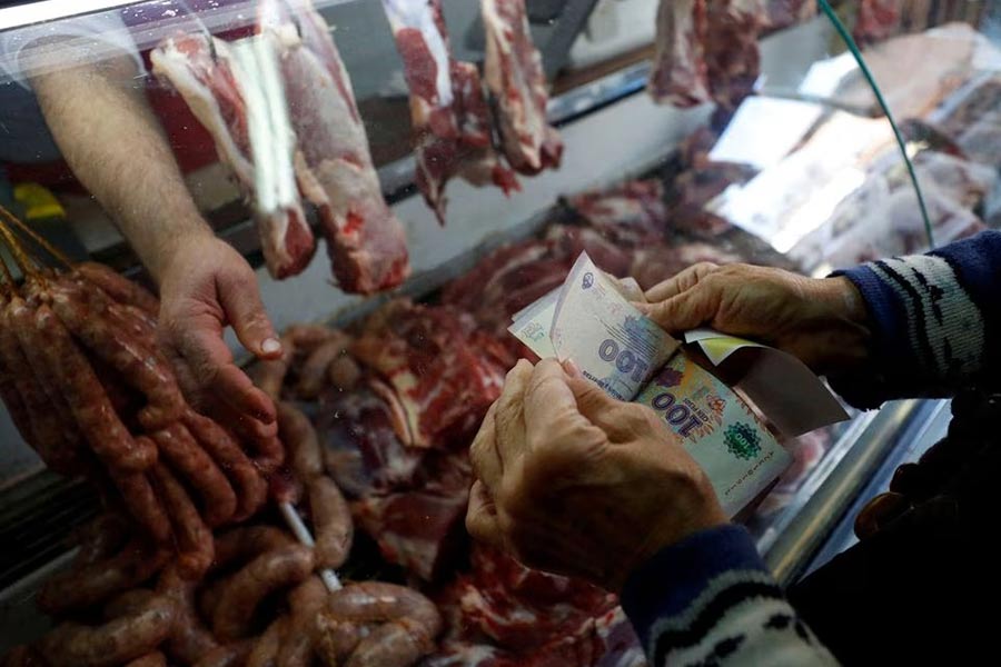 A customer counting money before paying at a butcher shop in Buenos Aires, the capital city of Argentina, last year –Reuters file photo