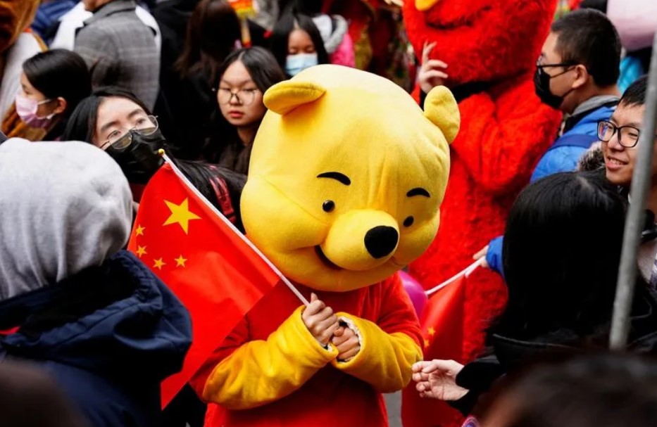 A parade participant in a Winnie the Pooh costume waves a Chinese flag before the Lunar New Year parade celebrating the Year of the Rabbit in the Chinatown neighborhood of New York, U.S., February 12, 2023. REUTERS/Bing Guan