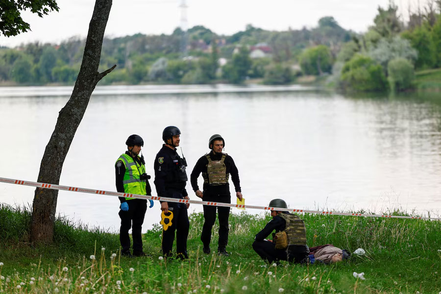 Police officers inspect the body of a man killed by a Russian missile strike on the bank of a lake, amid Russia's attack on Ukraine, in Kharkiv, Ukraine May 19, 2024.