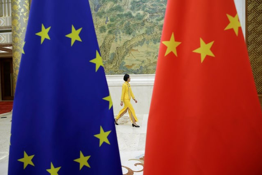 An attendant walks past EU and China flags ahead of the EU-China High-level Economic Dialogue at Diaoyutai State Guesthouse in Beijing, China June 25, 2018.