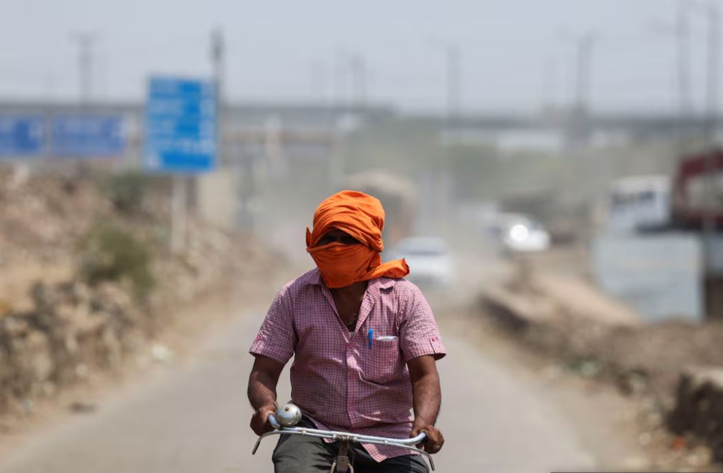 A man rides his cycle near a landfill site on a hot summer day during a heatwave in New Delhi, India, May 27, 2024. REUTERS/Anushree Fadnavis