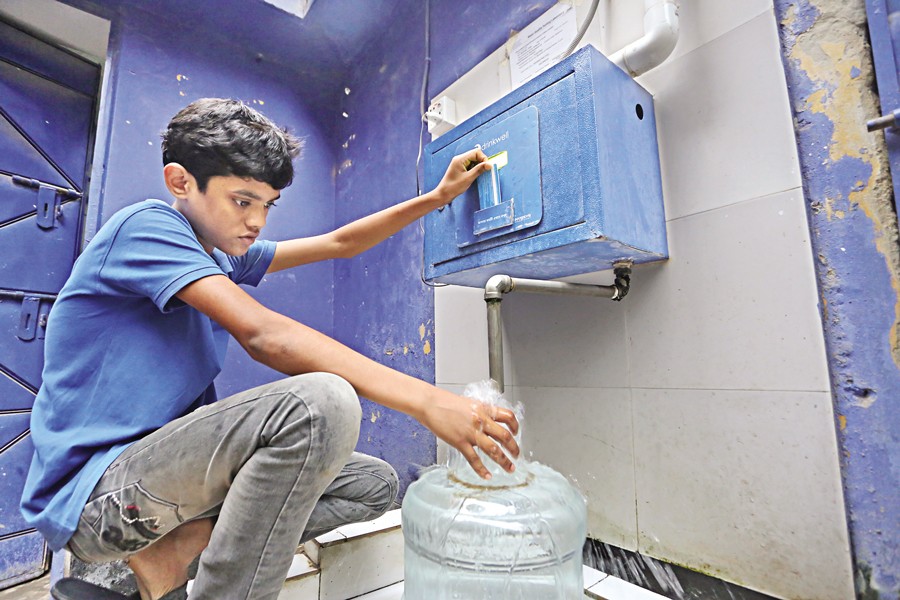 A boy collecting water from a Water ATM Booth of Wasa at Shantibagh in the capital — FE file photo