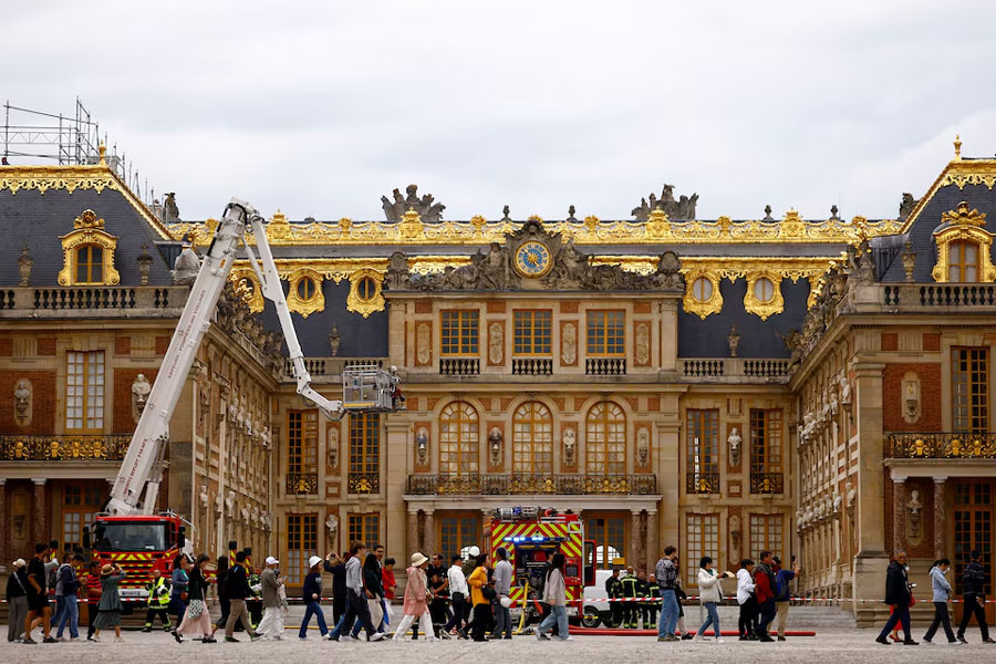 Visitors walk past as French firefighters work after a fire broke out at the Chateau de Versailles forcing the site's evacuation, but was swiftly brought under control, in Versailles, near Paris, France, June 11, 2024.