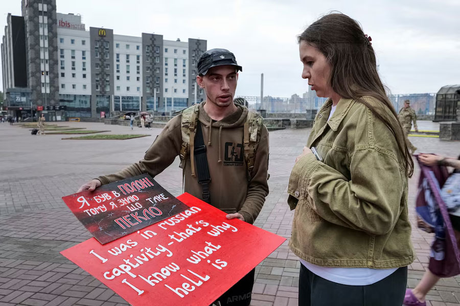 Svitlana Bilous, a 34-year-old civic activist and the wife of a Ukrainian soldier missing in action, and Illia Illiashenko, a Ukrainian former prisoner of war who was captured by Russian forces in Mariupol in 2022, look at posters before their bus tour to Switzerland to advocate for Ukrainian soldiers in Russian captivity, amid Russia's attack on Ukraine, in Kyiv, Ukraine June 12, 2024.