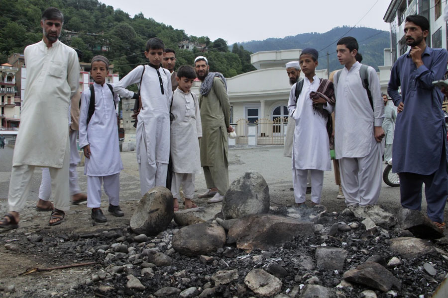 Local residents look at a spot where a Muslim mob lynched and burned a man over allegations that he had desecrated Islam's holy book, the Quran, in Madyan in Pakistan's Khyber Pakhtunkhwa province, Friday, June 21, 2024. The attackers also torched a police station which had held the man in Madyan and burned police vehicles parked there, according to local police official Rahim Ullah.