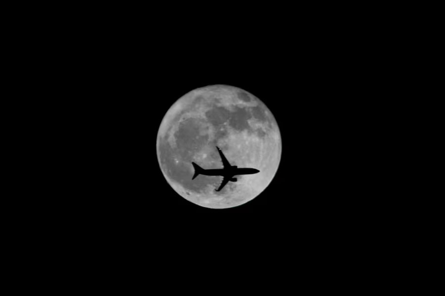 A passenger plane passes the moon as it comes into land at the international airport in Chennai, India, September 25, 2018.