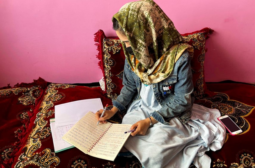 Sofia, an Afghan student, takes notes during an online class, at her house in Kabul, Afghanistan, March 18, 2023. REUTERS/Sayed Hassib