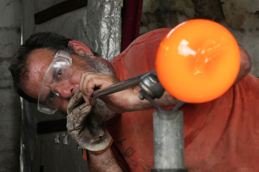 Glassmaker Eduardo Viciana blows molten glass in his atelier in Havana, Cuba, June 21, 2024.