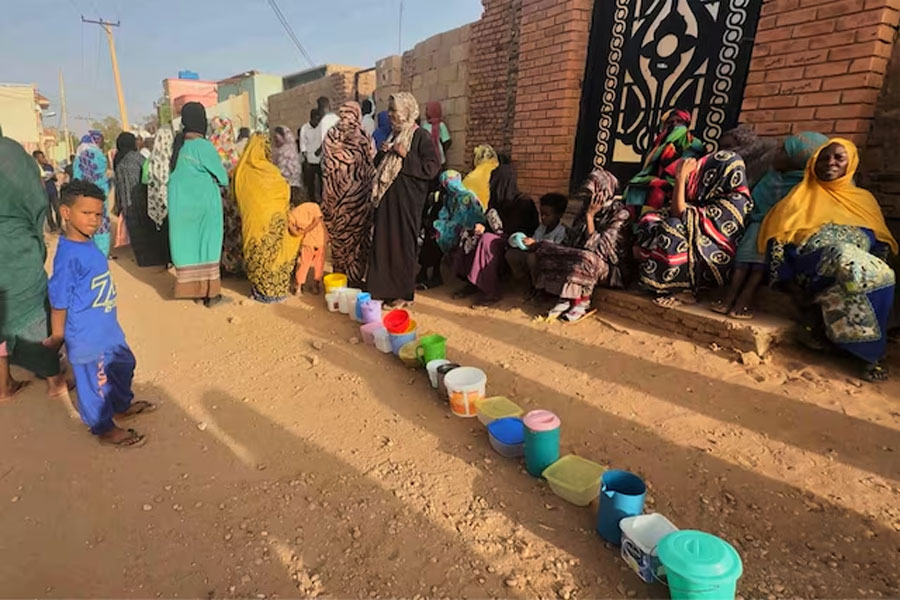 Residents wait to collect food in containers from a soup kitchen in Omdurman, Sudan March 11, 2024.