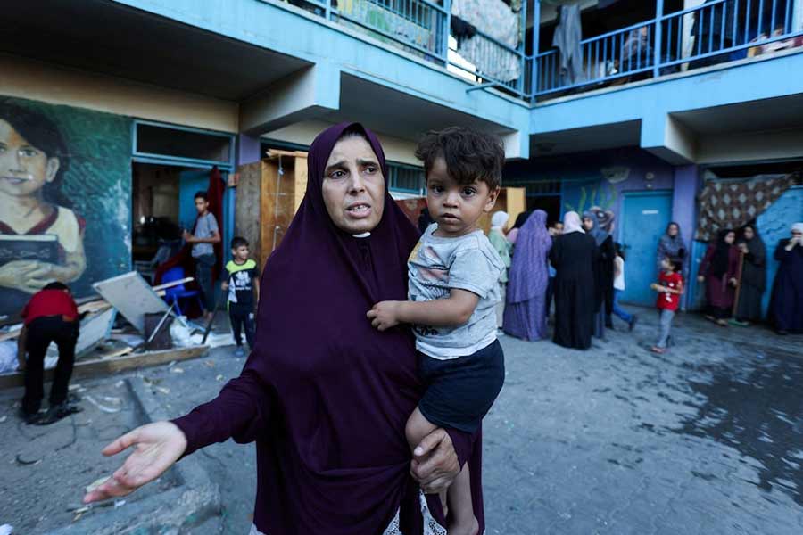 A Palestinian woman carrying a child reacting after an Israeli air strike on a UN school sheltering displaced people in Nusairat in central Gaza Strip of Palestine on Saturday –Reuters photo