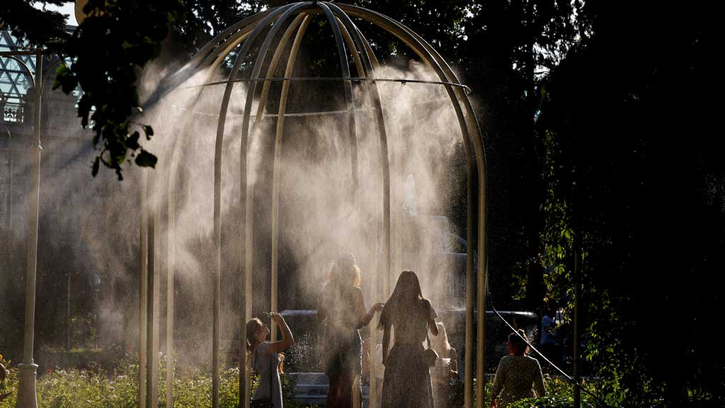 FILE PHOTO: People cool off by a mist cooling system in a park during hot weather in Moscow, Russia Jul 2, 2024. REUTERS/Evgenia Novozhenina/File Photo