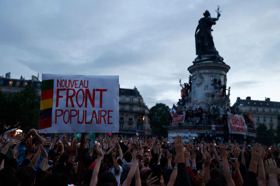 People raise their arms and hands as they gather at the Place de la Republique after partial results in the second round of the early French parliamentary elections, in Paris, France, July 7, 2024. The slogan reads "the "Nouveau Front Populaire (New Popular Front - NFP)"