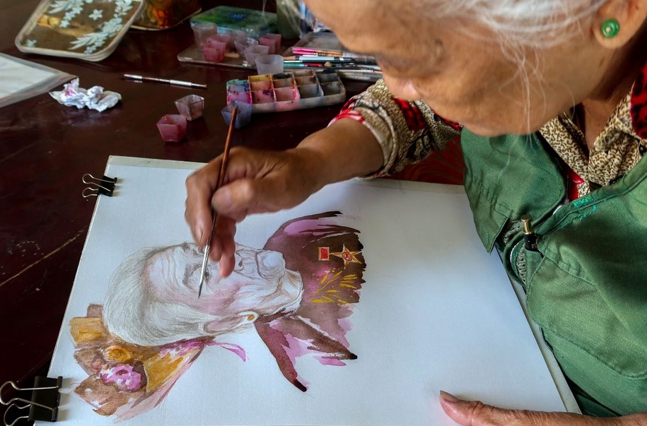 Vietnamese artist, Dang Ai Viet, paints a portrait of a woman as a part of her project, "heroic mothers of Vietnam", a term recognised by the Vietnam government for women who lost their husbands and sons to the Vietnam War, in Cao Lanh city, Dong Thap province, Vietnam, March 8, 2023. REUTERS/Thinh Nguyen