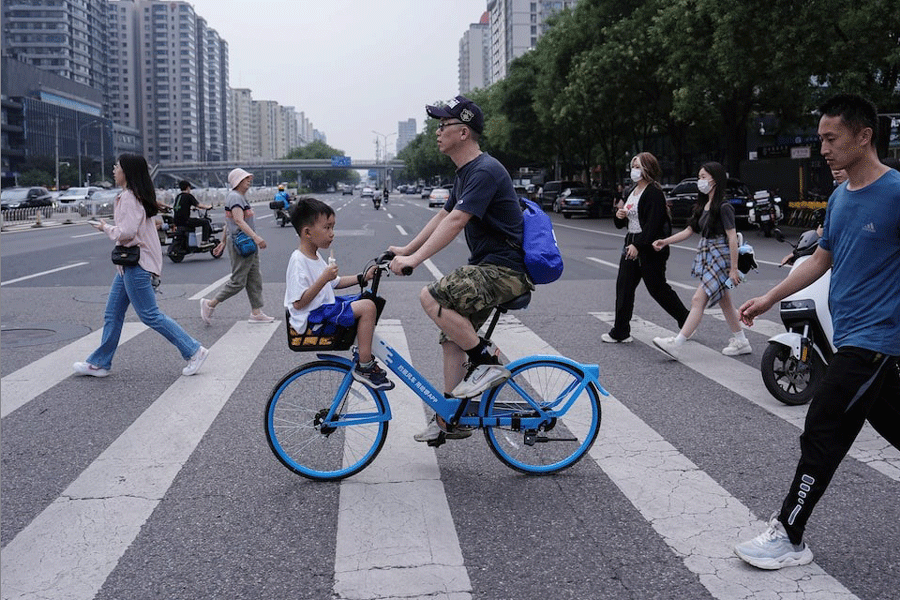 A person rides a bicycle with a child sitting in the basket in Beijing, China July 14, 2024.