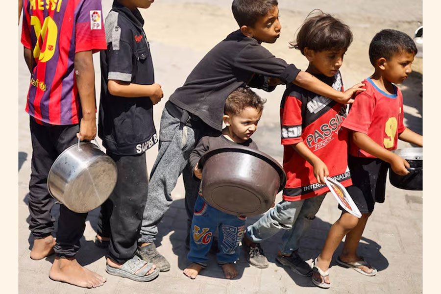 Palestinian children gather to receive food cooked by a charity kitchen, amid food scarcity, as Israel-Hamas conflict continues, in Khan Younis in the southern Gaza Strip, June 26, 2024.