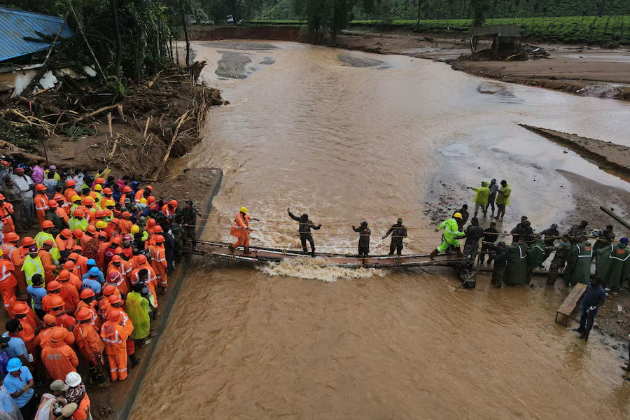 A drone view shows members of rescue teams crossing a temporary bridge to reach to a landslide site after multiple landslides in the hills in Wayanad district, in the southern state of Kerala, India, July 31, 2024.