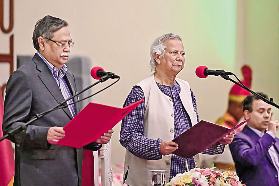 Muhammad Yunus (C) takes the oath of office as the chief adviser of Bangladesh's new interim government during the oath-taking ceremony administered by President Mohammed Shahabuddin (L) in Dhaka on Thursday. — AFP