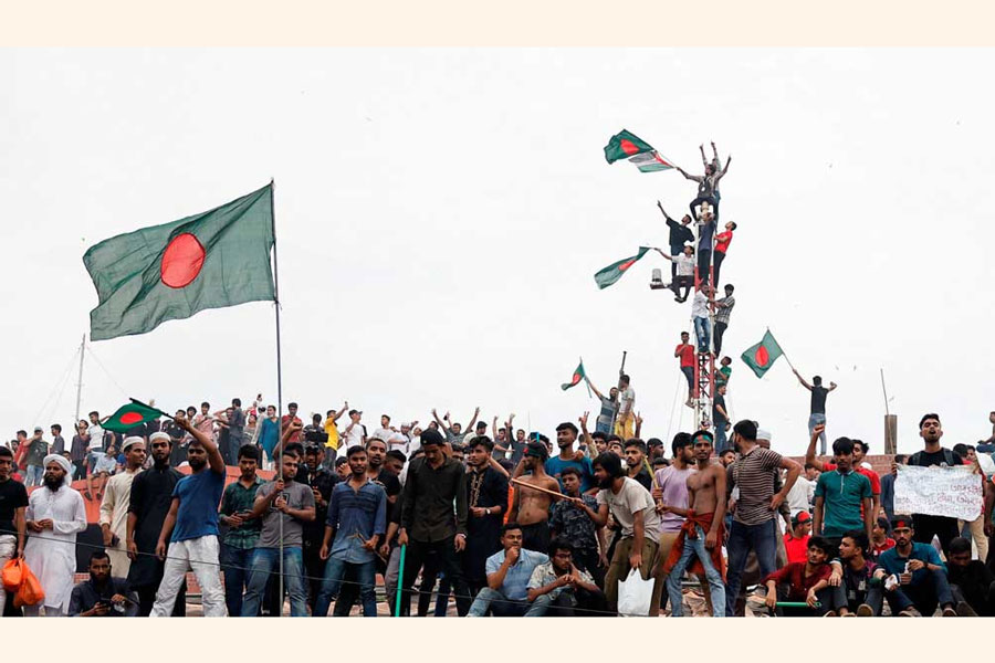 People waves Bangladeshi flags on top the Ganabhaban, the Prime Minister’s residence, as they celebrate the resignation of PM Sheikh Hasina in Dhaka, Bangladesh, August 5, 2024.