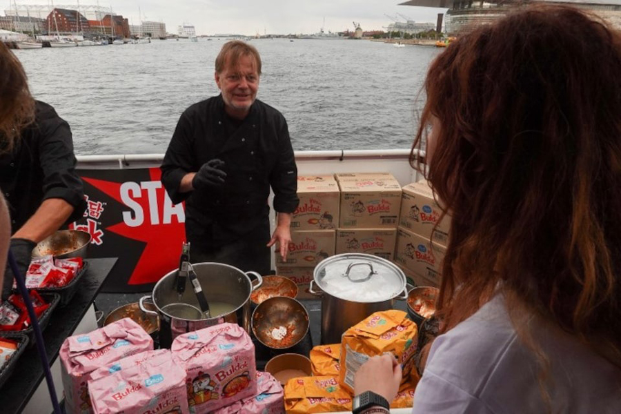 Cooks serve Buldak ramen to passengers on a boat on a ramen at a media event for the product in central Copenhagen, Denmark, August 8, 2024.