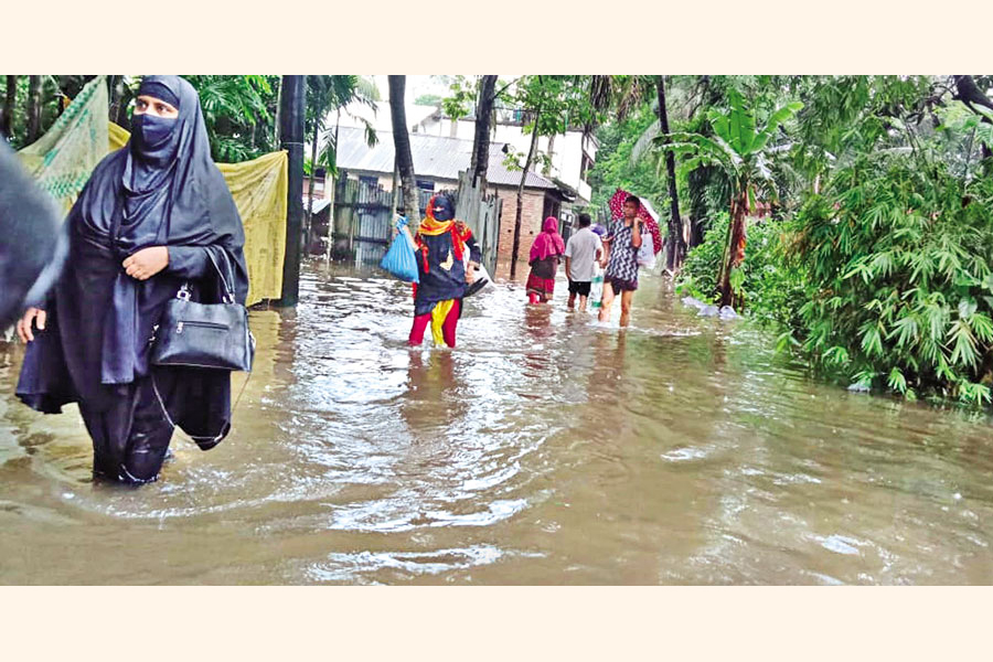 People wade through floodwater in Jaksin Bazar area of Laxmipur Sadar upazila on Monday. — Focus Bangla