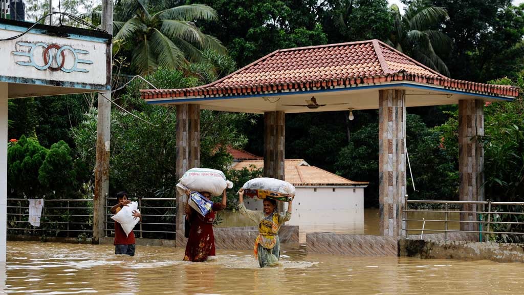 People carrying sacks, wade through flood water, amid severe flooding in the Fazilpur area of Feni, Bangladesh, Aug 26, 2024.