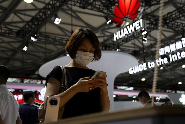 A visitor checks a mobile phone near the Huawei logo during the Mobile World Congress in Shanghai, China June 28, 2023.