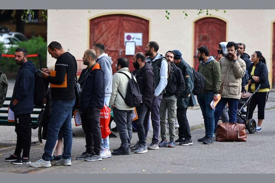 Migrants queue in a waiting area to be escorted to a registration office at the arrival centre for asylum seekers in Reinickendorf district, Berlin, Germany, October 6, 2023.