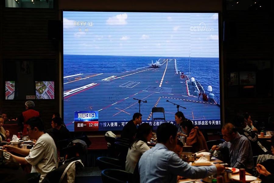 Customers dine near a giant screen broadcasting news footage of aircraft under the Eastern Theatre Command of China's People's Liberation Army (PLA) taking part in a combat readiness patrol and "Joint Sword" exercises around Taiwan, at a restaurant in Beijing on Monday –Reuters photo