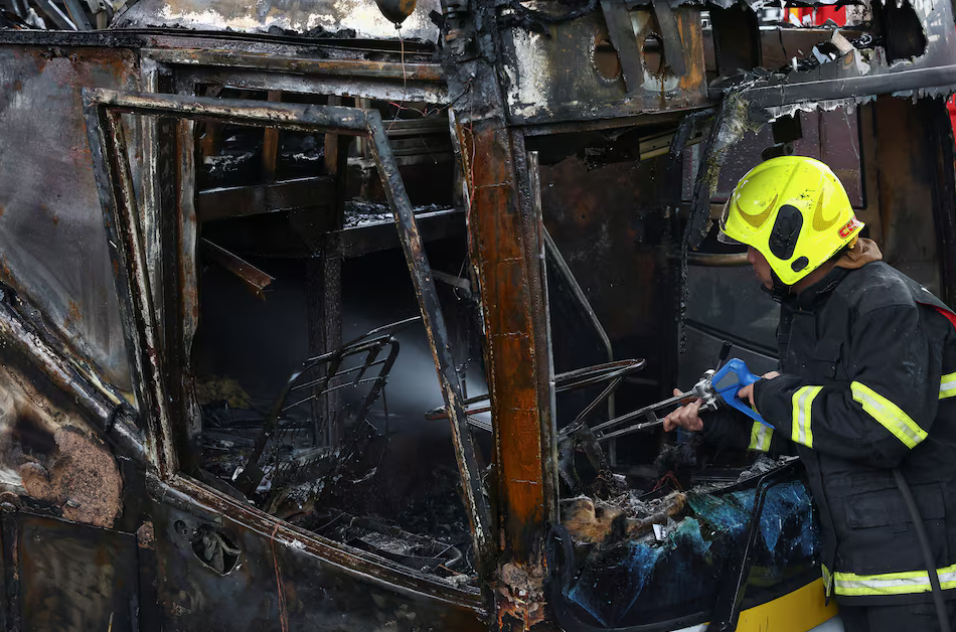 Firefighter works to extinguish a burning bus that was carrying teachers and students from Wat Khao Phraya school, reportedly killing almost a dozen, on the outskirts of Bangkok, Thailand, October 1, 2024. REUTERS/Chalinee Thirasupa