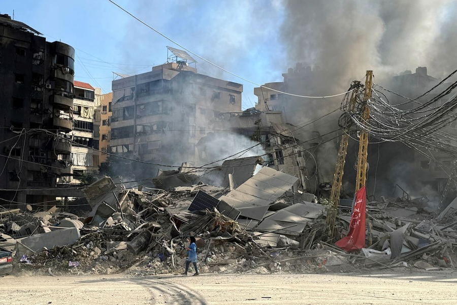 A woman walks past damaged buildings and debris in the aftermath of a strike, amid ongoing hostilities between Hezbollah and Israeli forces, in Beirut’s southern suburbs, Lebanon October 3, 2024.