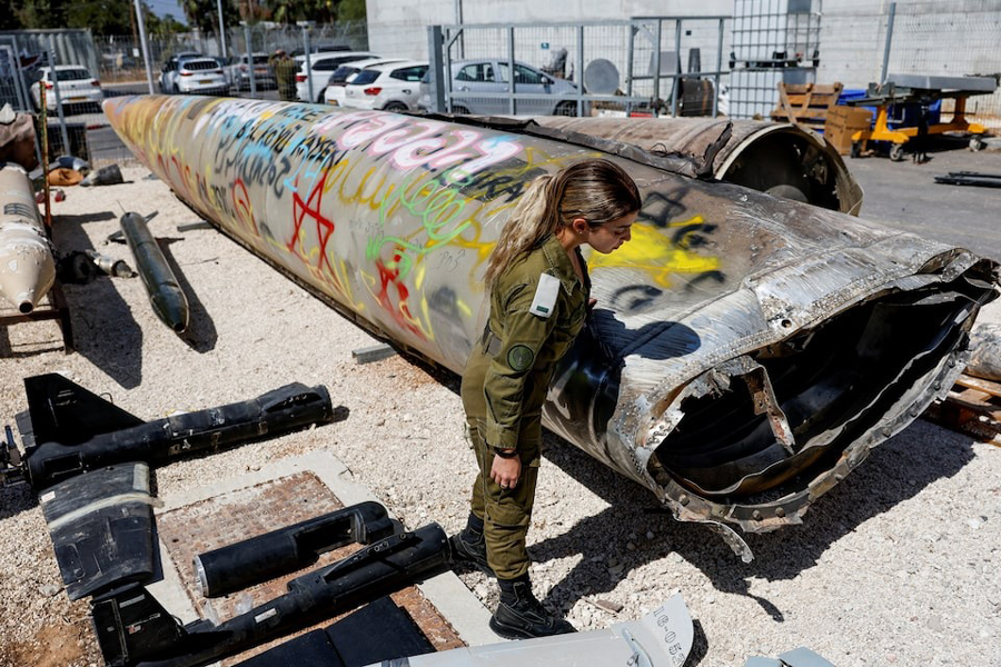 An Israeli soldier stands next to the remains of an Emad ballistic missile at Julis army base, October 9, 2024.