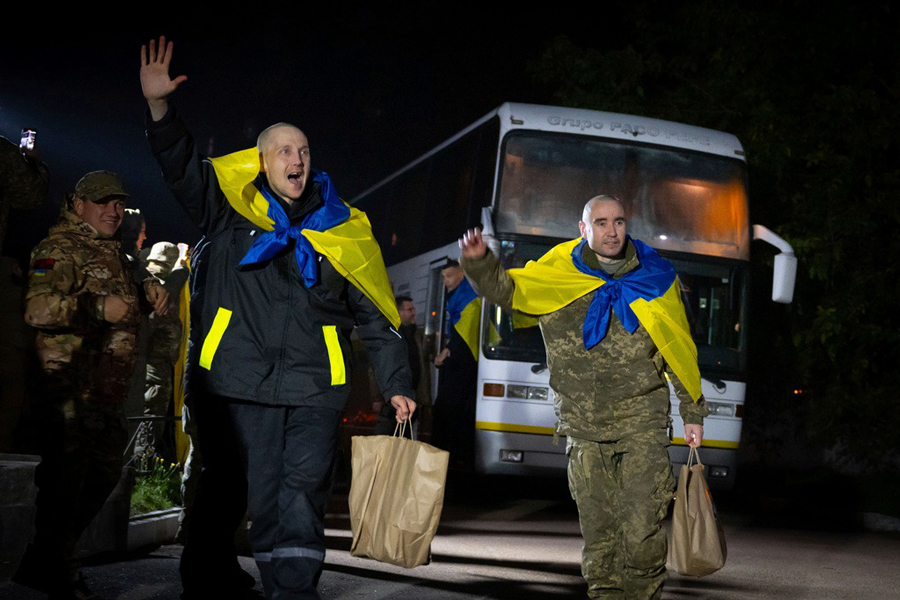 In this photo provided by the Press Service of the President of Ukraine on Oct 19, 2024, Ukrainian servicemen shout, "Glory to Ukraine," with National flags after returning from captivity during a POWs exchange in an undisclosed location, Ukraine.